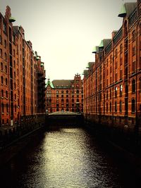 Canal in city against clear sky