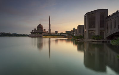 Mosque by calm lake against sky