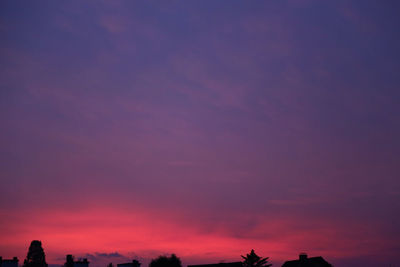 Low angle view of silhouette trees against dramatic sky