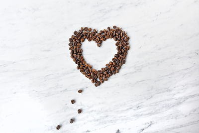 High angle view of coffee beans arranged in heart shape on marble table