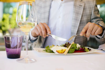 Midsection of man with food on table at restaurant