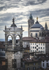 Buildings in city against cloudy sky