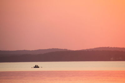 Silhouette boat in lake against sky during sunset