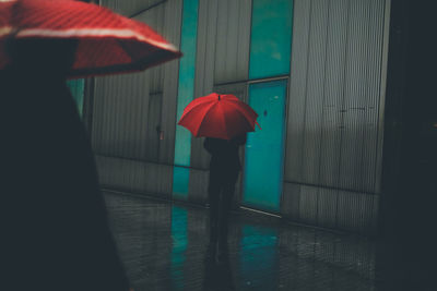 Rear view of woman with umbrella walking in rain