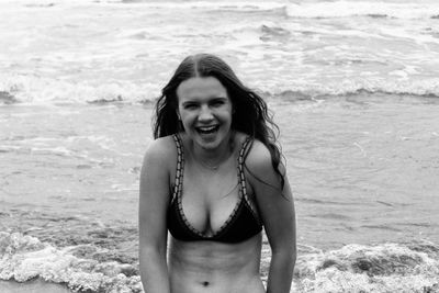 Happy teenage girl in bikini on shore at beach
