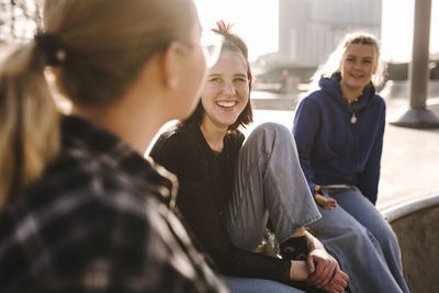 Smiling teenage girls sitting in skatepark