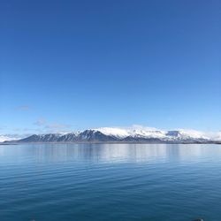 Scenic view of lake by snowcapped mountain against sky