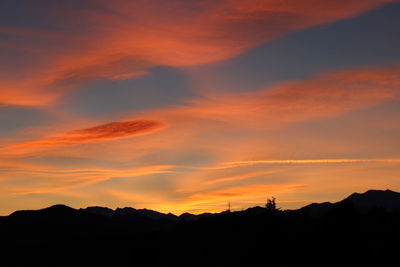 Silhouette landscape against dramatic sky during sunset