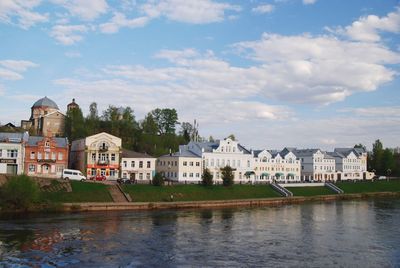 Buildings by river against sky in city