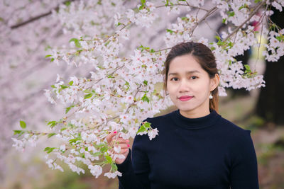 Portrait of beautiful woman standing by flowering tree