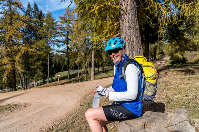 Smiling woman sitting on rock in forest