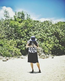 Rear view of woman standing against trees