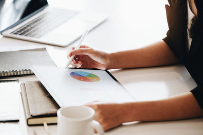 Midsection of woman using laptop on table