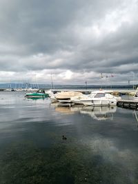 Boats moored at harbor against cloudy sky