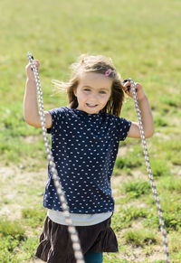 Portrait of smiling girl holding rope at park