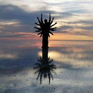 Silhouette palm tree on beach against sky at sunset