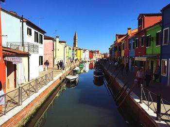 Boats moored in canal against clear blue sky