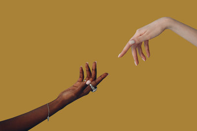 Cropped hand of woman gesturing against yellow background