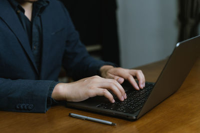Midsection of man using laptop on table