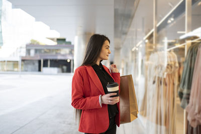 Young woman looking away while standing at store