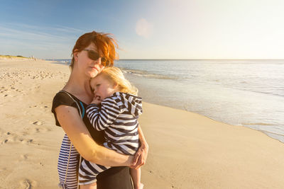 Happy friends at beach against sky