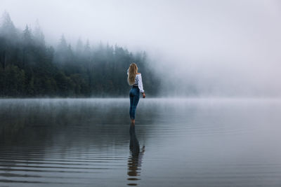 Full length of man in lake during foggy weather