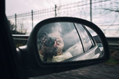 Reflection of man on side-view mirror