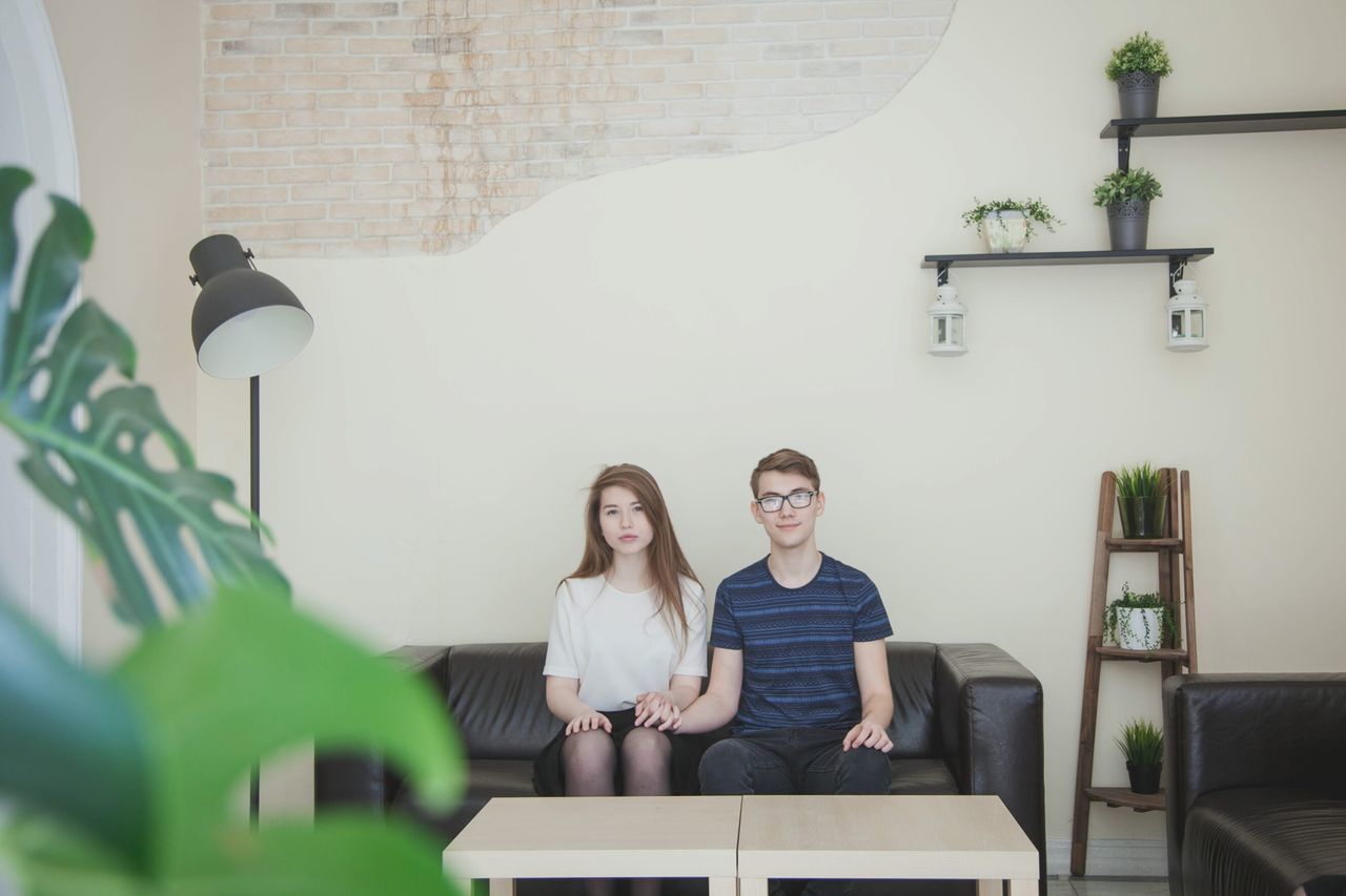 PORTRAIT OF YOUNG WOMAN SITTING ON CHAIR