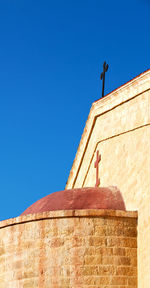 Low angle view of cross on roof against clear sky