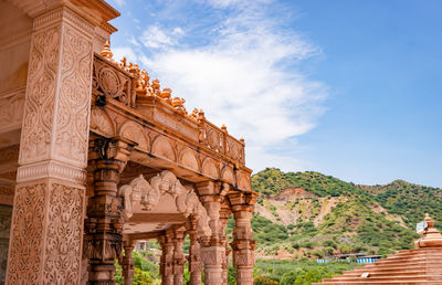 Artistic hand carved red stone jain temple with bright blue sky at morning from unique angle