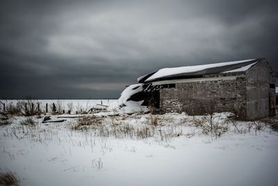 Snow covered landscape against cloudy sky