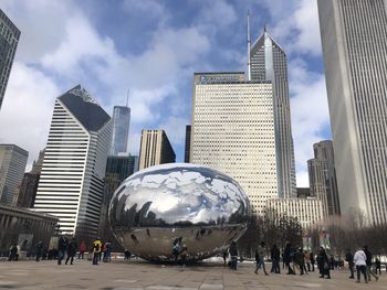 People on modern buildings in city against sky