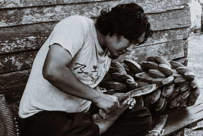 Side view of young man sitting on wood