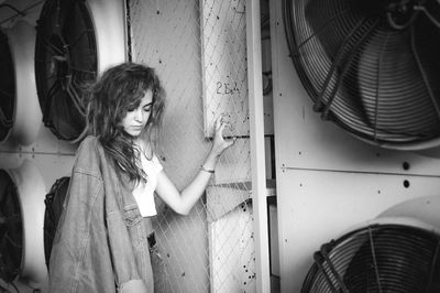 Teenage girl standing against exhaust fans