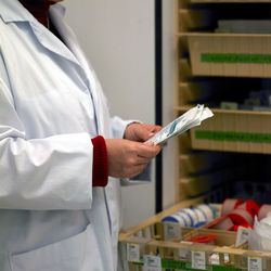 Midsection of doctor holding medical papers by drawers