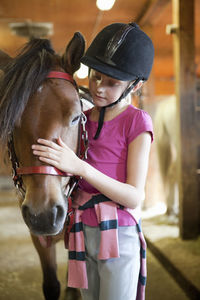 Girl with horse in stable