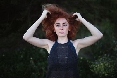 Portrait of young woman standing against tree