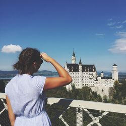 Rear view of woman standing against sky in city