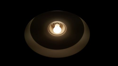 Close-up of illuminated light bulb over black background