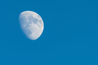 Low angle view of moon against clear blue sky