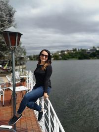 Portrait of smiling young woman in water against sky