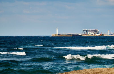 Lighthouse by sea against sky