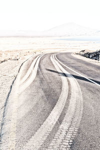 Tire tracks on road against clear sky