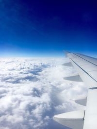 Aerial view of airplane wing flying over clouds