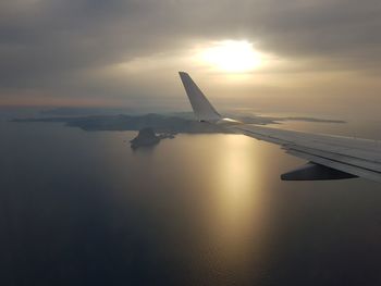 Cropped image of airplane over sea against sky