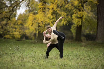 Young couple dancing on grassy field at park