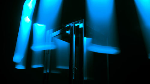 Close-up of illuminated lighting equipment on wall in darkroom