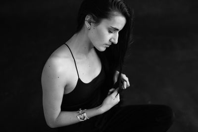 Side view of young woman standing against black background