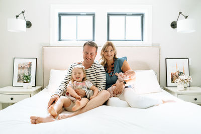 A family of four sitting together in a modern bedroom