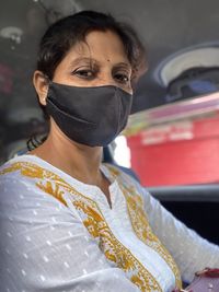 Portrait of woman wearing mask driving car